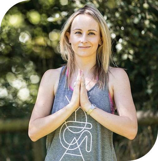 Nicola Chantler standing in front of trees, holding her hands together in a prayer position