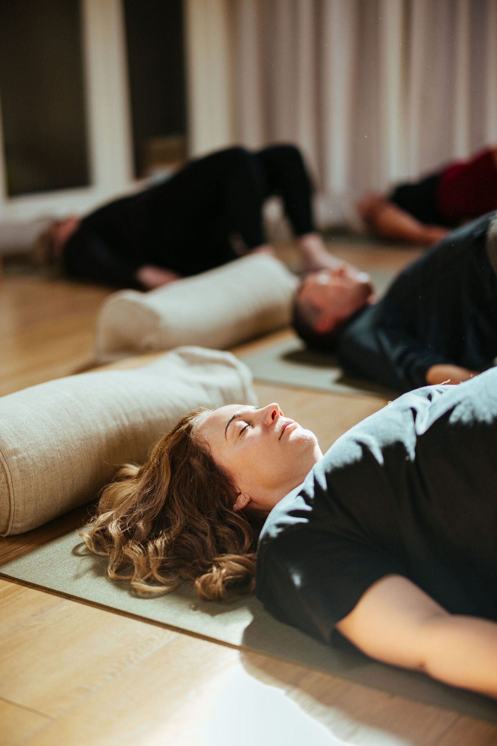 people lying down on yoga mat, with eyes closed